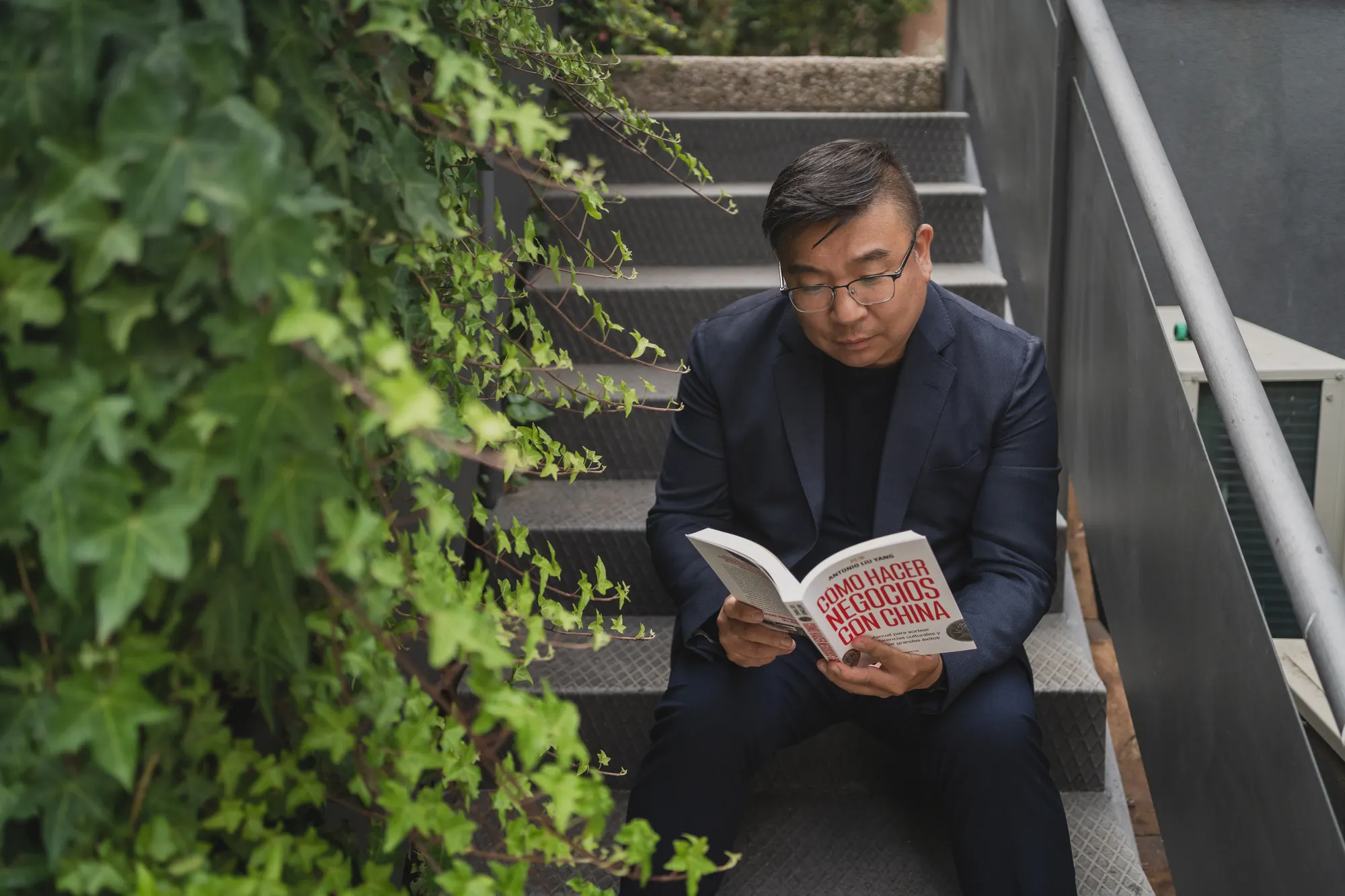 Antonio Liu Yang leyendo «Cómo hacer negocios con China» sentado en una escalera